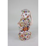 A Chinese pottery figure of a monkey, seated holding a fruit, with all over polychrome decoration of