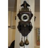 A 20th century weight driven wall clock, with pierced brass pediment mounted by a figural finial,