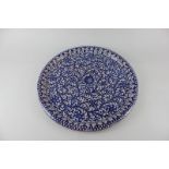 A Persian style pottery circular platter, with blue and white pomegranate and foliate decoration,