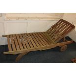 A wooden garden recliner, slatted construction with end handles, wooden wheels and adjustable