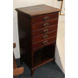 An early 20th century mahogany music cabinet with five drawers with fold-down fronts, above open