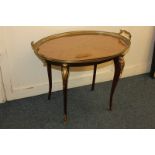 A Louis XVI style gilt metal oval tray top side table with glass top and two handles, on cherub