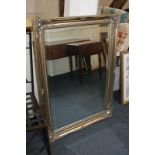 A modern gilt framed rectangular wall mirror with scroll and foliate decoration and bevelled