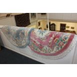 Two Chinese oval rugs, one pink ground, the other green, both with floral decoration, largest