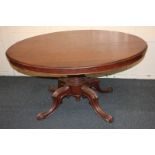 A Victorian mahogany loo table with oval tilting top, on baluster turned stem and four scrolling
