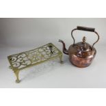 A brass trivet the pierced rectangular form on paw feet, together with a copper kettle