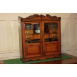 An early 20th century oak smokers cabinet, the two bevelled glass panel doors enclosing an