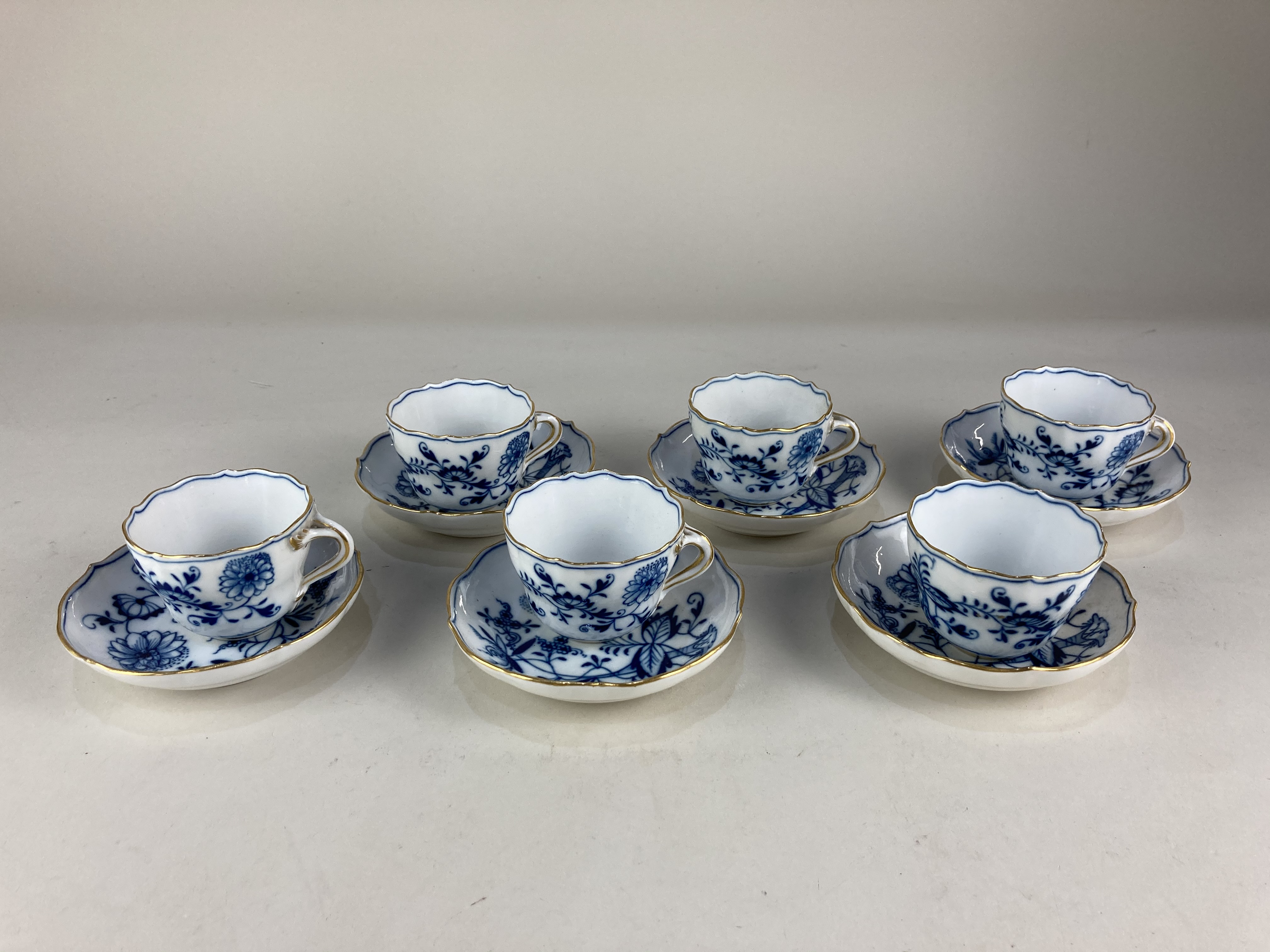 A set of six Meissen porcelain 'onion' pattern blue and white coffee cups and saucers, with floral