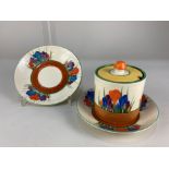 A Clarice Cliff Bizarre Crocus pattern preserve pot and cover, 7.5cm, and two saucers, 14cm