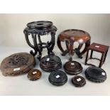 A collection of fourteen Chinese hardwood stands, most carved, together with a Chinese black lacquer