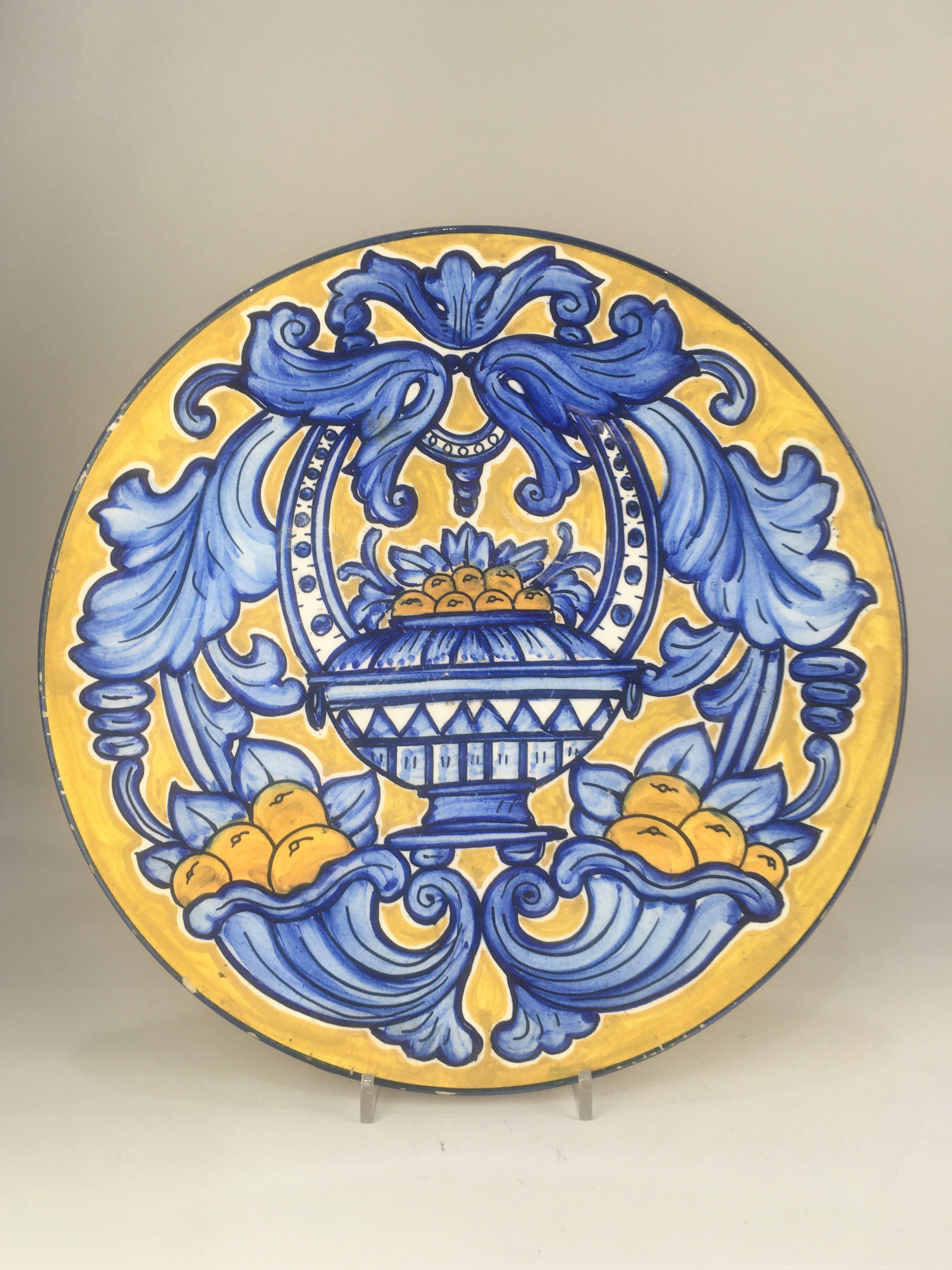 A Continental maiolica style wall plate, decorated with fruit filled cornucopia and vase, in