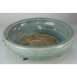 A Chinese glazed celadon bowl, raised on three feet, 30cm diameter (stapled)
