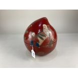 A Japanese red lacquered box in the form of a peach, decorated with a figure, possibly Shoulao,