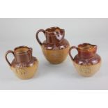 A collection of three Doulton Lambeth glazed brown stoneware jugs, decorated in raised relief with