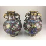 A pair of cloisonné two-handled vases, of footed baluster form, with floral decoration on rust