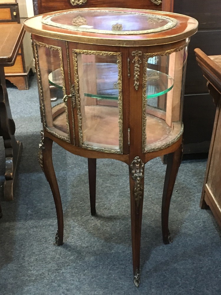 A late 19th century French gilt metal mounted oval vitrine, with two bowed glazed panel doors