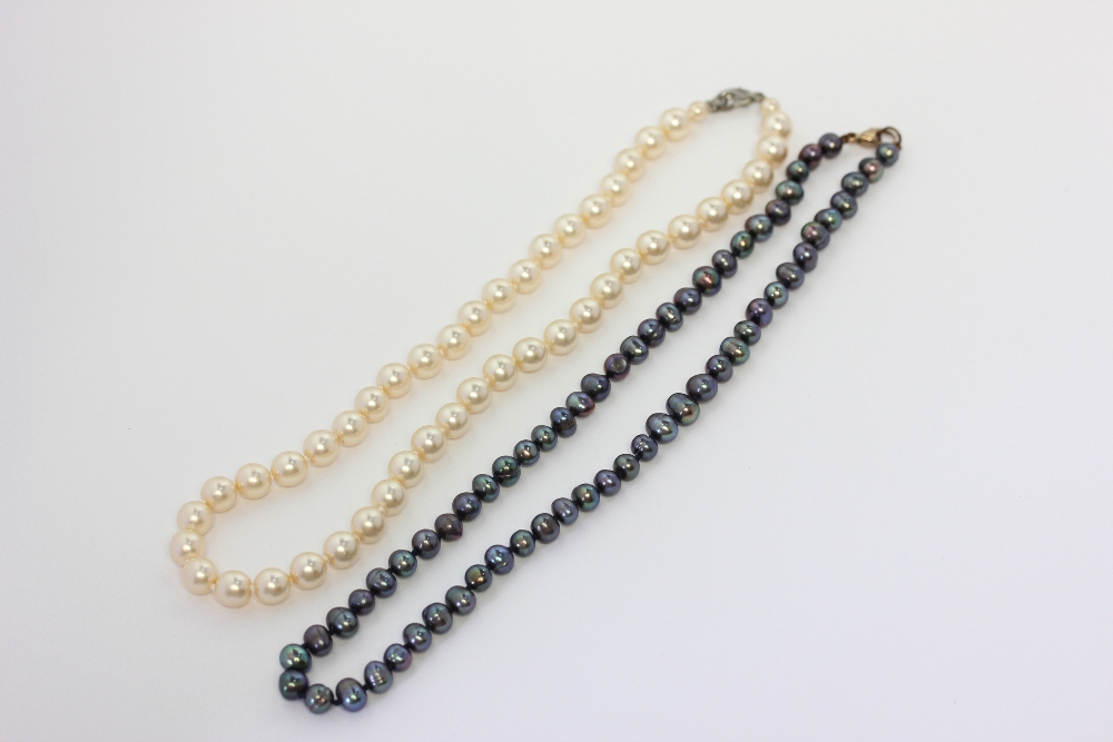 A black pearl necklace on a gold lobster claw clasp; and an imitation pearl necklace