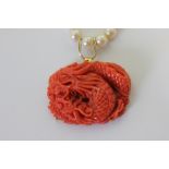 A coral and pearl necklace hung with a carved coral dragon pendant and with 14ct gold mounts