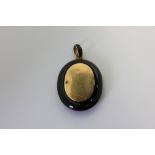 A Victorian black onyx and gold mourning locket on black enamel bale (a/f)