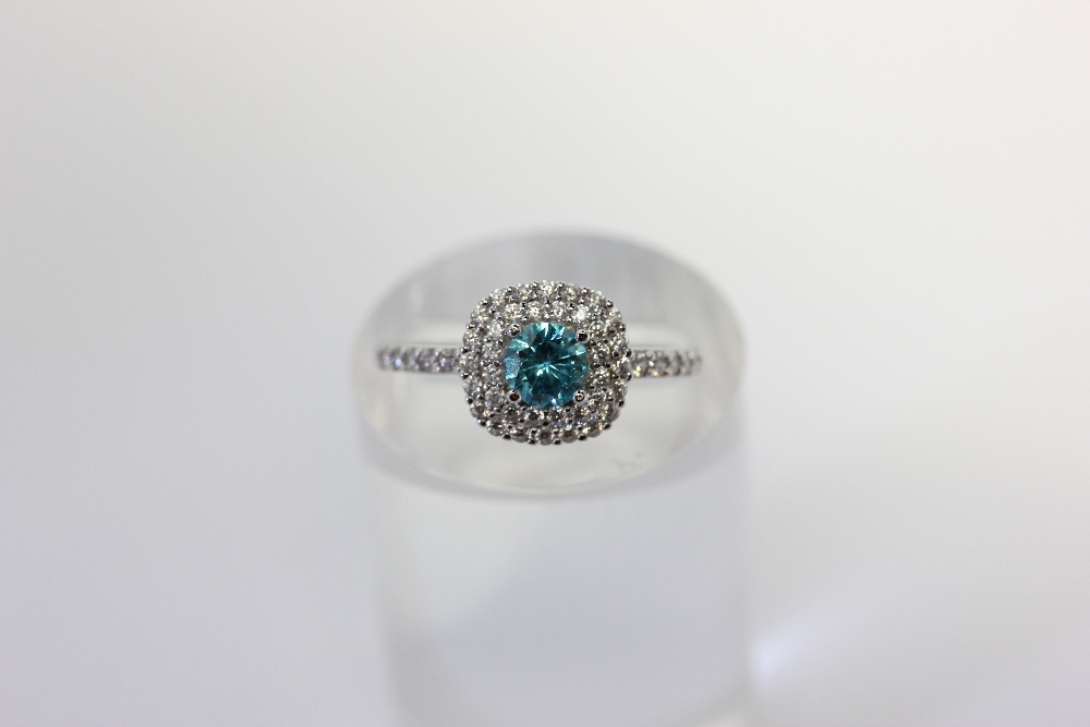 A zircon cluster ring with a central blue stone within a two row white stone border