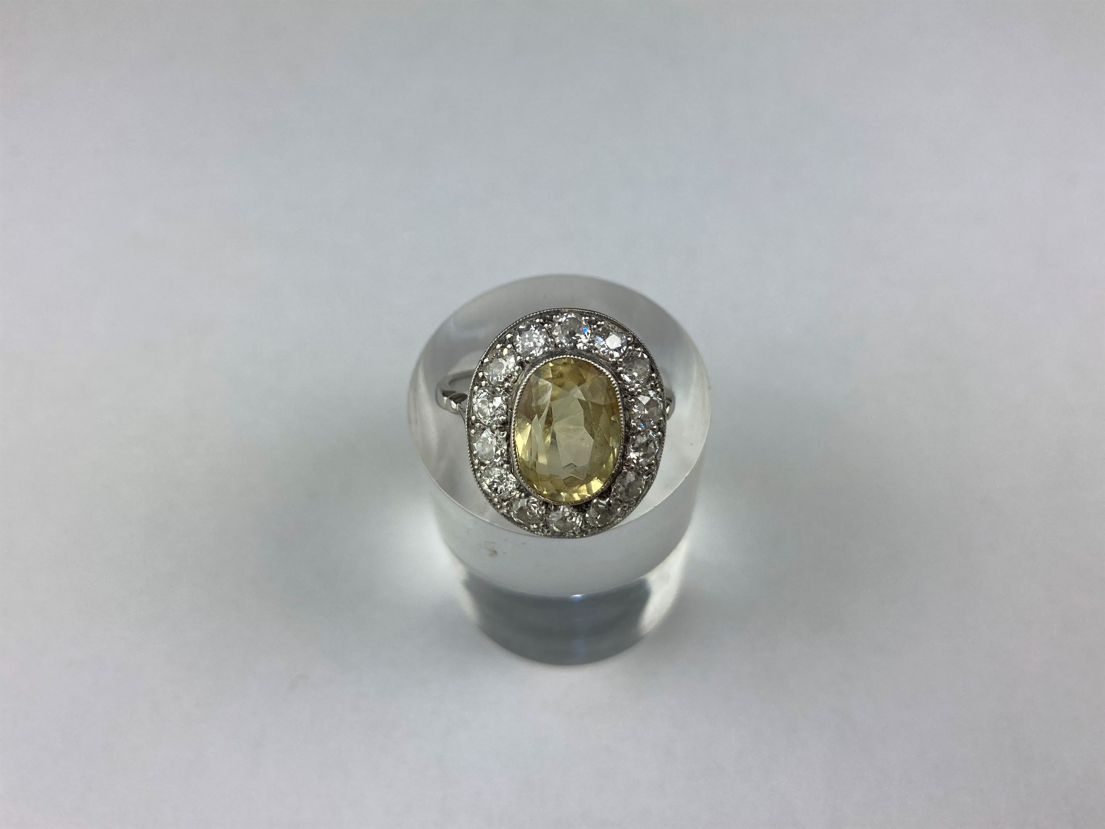 A yellow sapphire and diamond cluster ring, the oval cut stone within a border of old cut diamonds