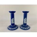 A pair of Wedgwood navy blue jasperware candlesticks tapered stems with raised classical muses on