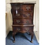 A small reproduction mahogany chest on stand style side table, with four drawers, on shell capped