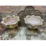 A pair of composition stone garden urns, with acanthus leaf bowls and socles, on integral square