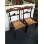 A pair of 19th century mahogany dining chairs with scroll carved bar backs, cane seats on sabre