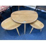 An Ercol nest of three pale wood 'pebble' tables, on cylindrical splayed legs, labelled, largest