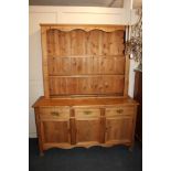 A modern pine dresser with three drawers and cupboards 154cm with an associated pine two shelf