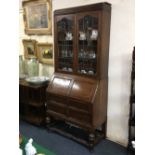 An early 20th century oak bureau bookcase, with two glazed panel doors enclosing shelves, above