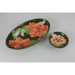 A Moorcroft 'Hibiscus' pottery oval dish, 23cm, and small circular dish, 9cm diameter, both