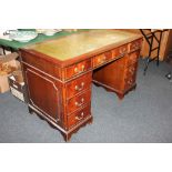 A mahogany pedestal desk, with green leather inset rectangular top above an arrangement of nine