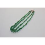 A jade bead necklace the two rows of graduated pale green mottled beads on a gold clasp