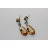 A pair of topaz and diamond drop earrings, the pear cut stones loose hung from millegrain set