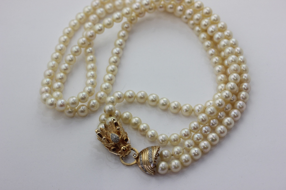 A two row cultured pearl necklace on an assembled gold and diamond clasp modelled as a dragon