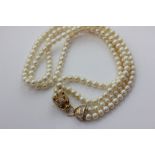 A two row cultured pearl necklace on an assembled gold and diamond clasp modelled as a dragon