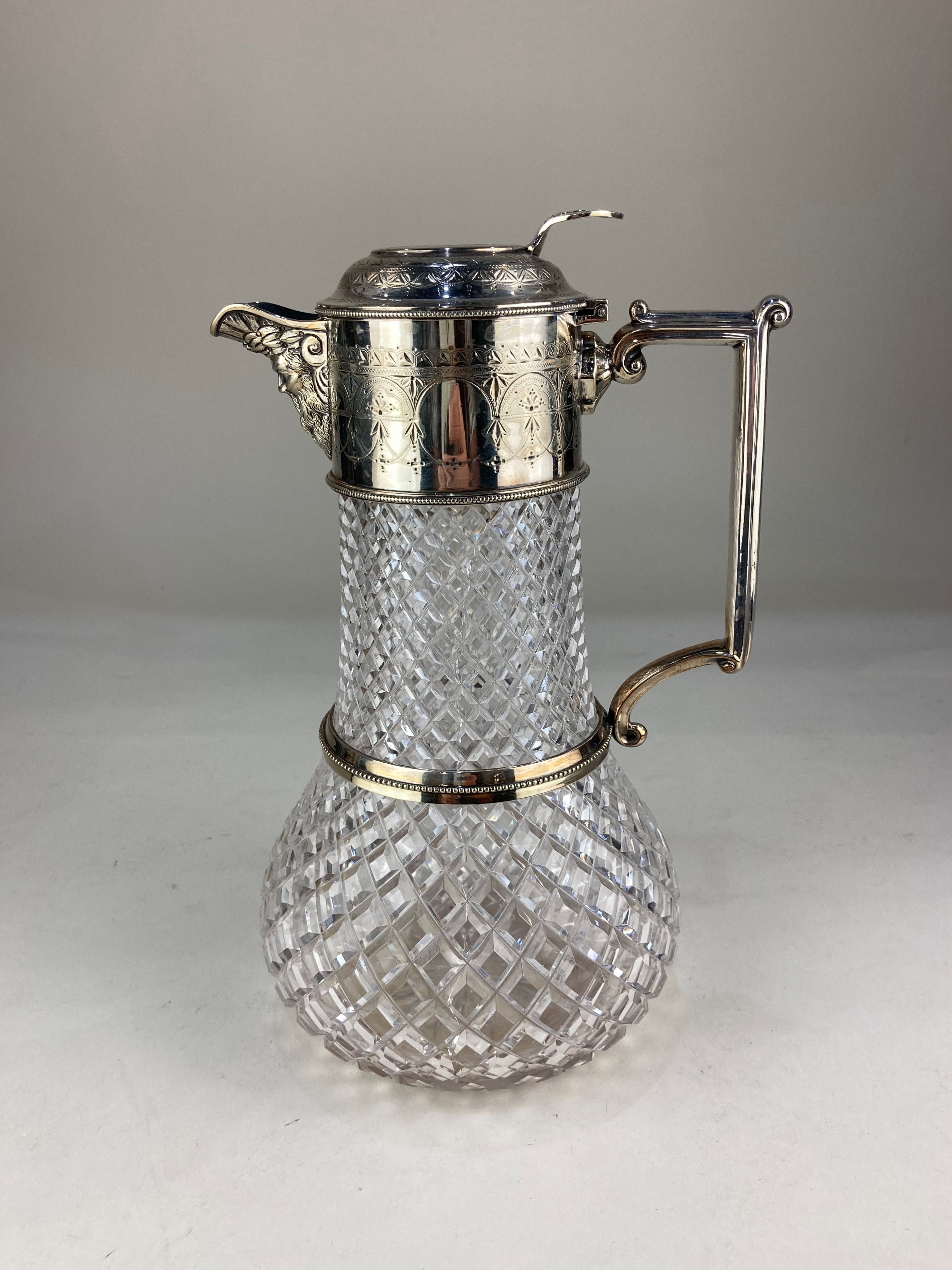 A silver plate mounted cut glass claret jug, with cast mask spout and engraved decoration (a/f)