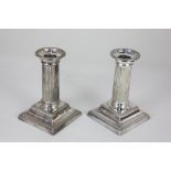 A pair of silver plated dwarf column candlesticks with detachable sconces on square swept bases,