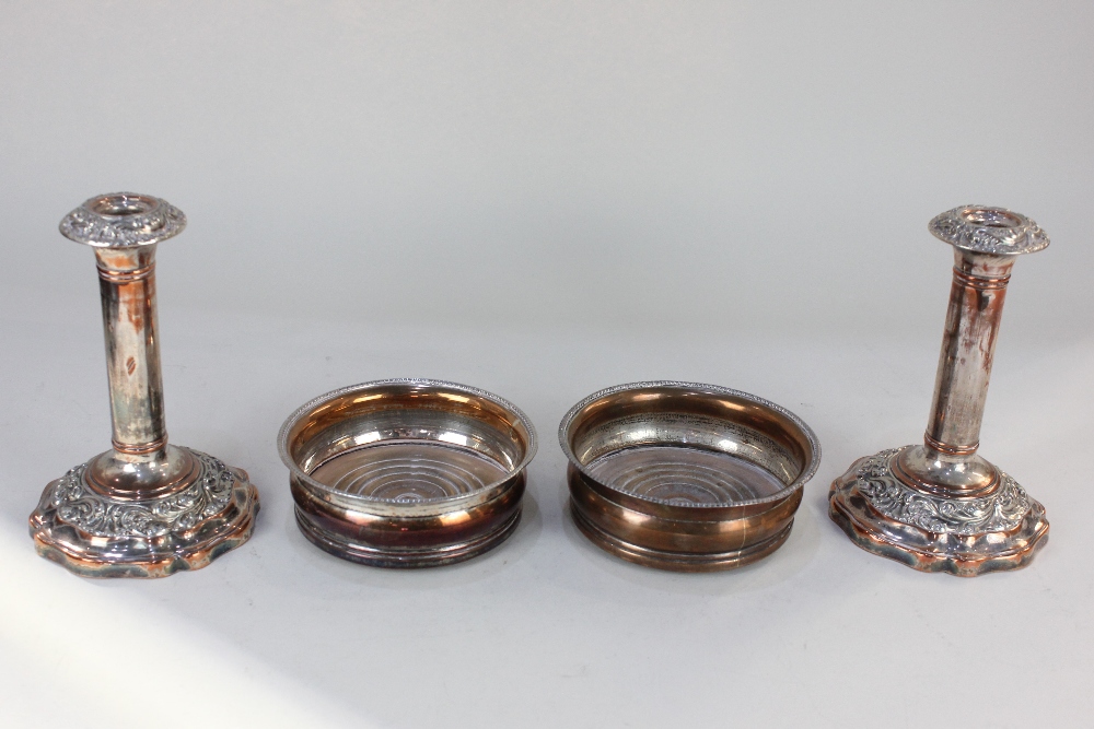 A pair of silver plated bottle coasters, and a pair of silver plated column candlesticks with