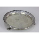 A Portuguese silver circular card tray with floral engraved pierced border on three cast paw feet,