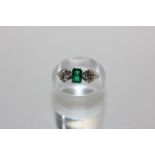 An emerald and diamond three stone ring claw set with a central set cut emerald with a double claw