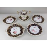 A Rockingham style china twin handle sugar bowl and cover, two shallow dishes and two plates,