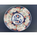 A large Japanese porcelain Imari charger, decorated with three scenes of gardens, the base with