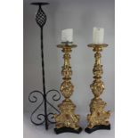 A pair of 17th century style ornate gilt candlesticks, mounted on black triform bases, 62cm high,