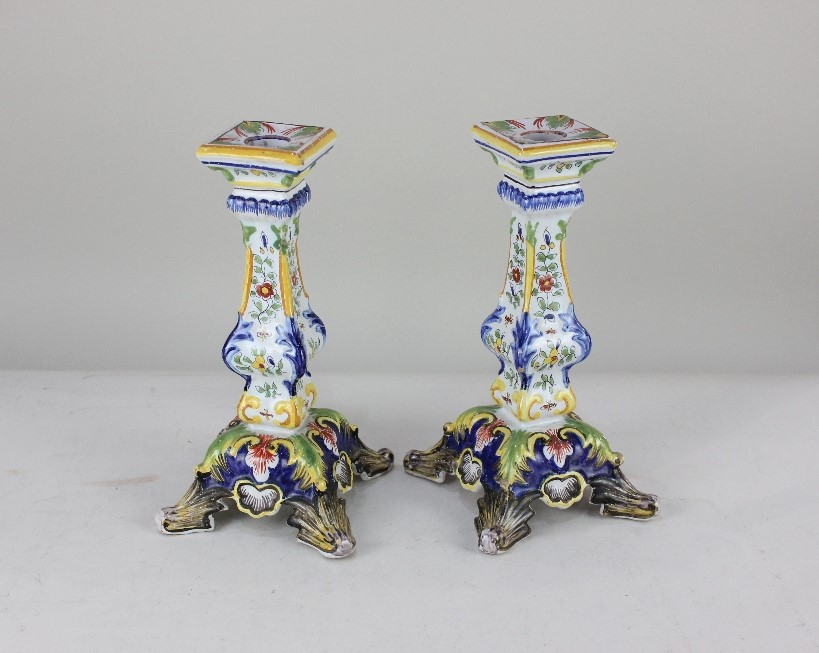 A pair of French faience candlesticks, decorated with flowers, on outswept feet, 24cm high