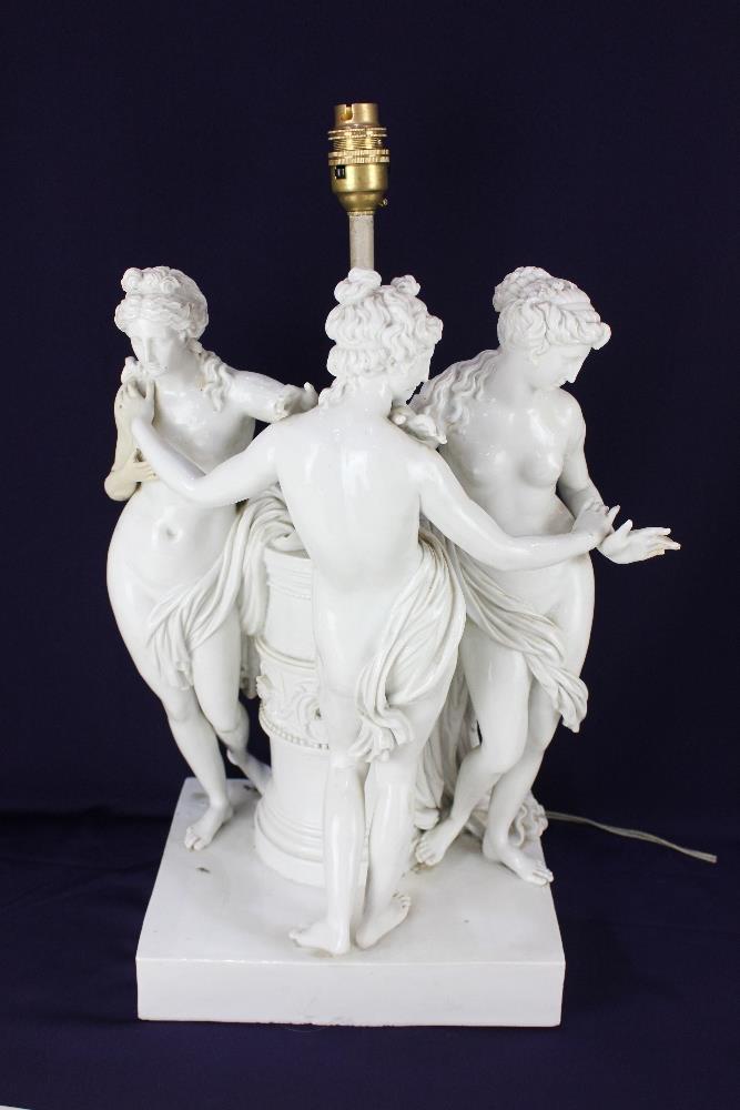 A white porcelain figural table lamp, in the form of the Three Graces around central column support,