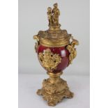 A gilt metal mounted red vase and cover the lid with two figures on oval body with griffin handles