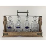 A Betjemann's patent brass mounted oak four decanter tantalus, containing four cut glass spirit